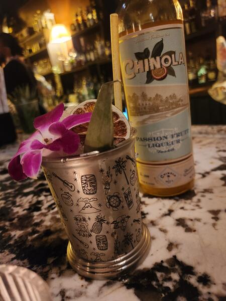 Chinola passion fruit liqueur cocktail in an engraved tiki mug